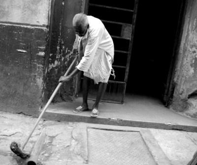 Woman cleaning in front of her home.  Photo: Caridad