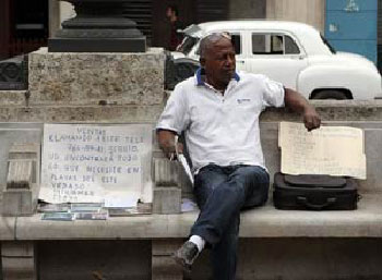 A real estate broker advertises homes with cardboard signs on the Paseo del Prado promenade. 