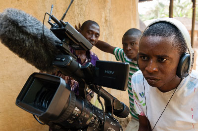 Barmmy checking on the photographic setting before filming. In the back is Joseph (left) and Solomon looking on. 