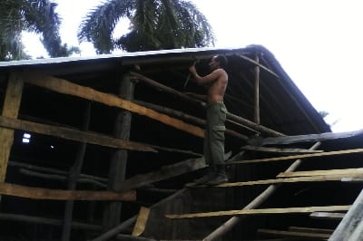 A farmer in eastern Cuba dismantles the room of his tobacco drying facility.